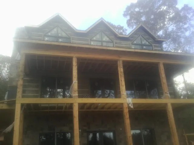 Dormers and porch framing on a large log home under construction — Roof Coating work by our crew in Center Conway