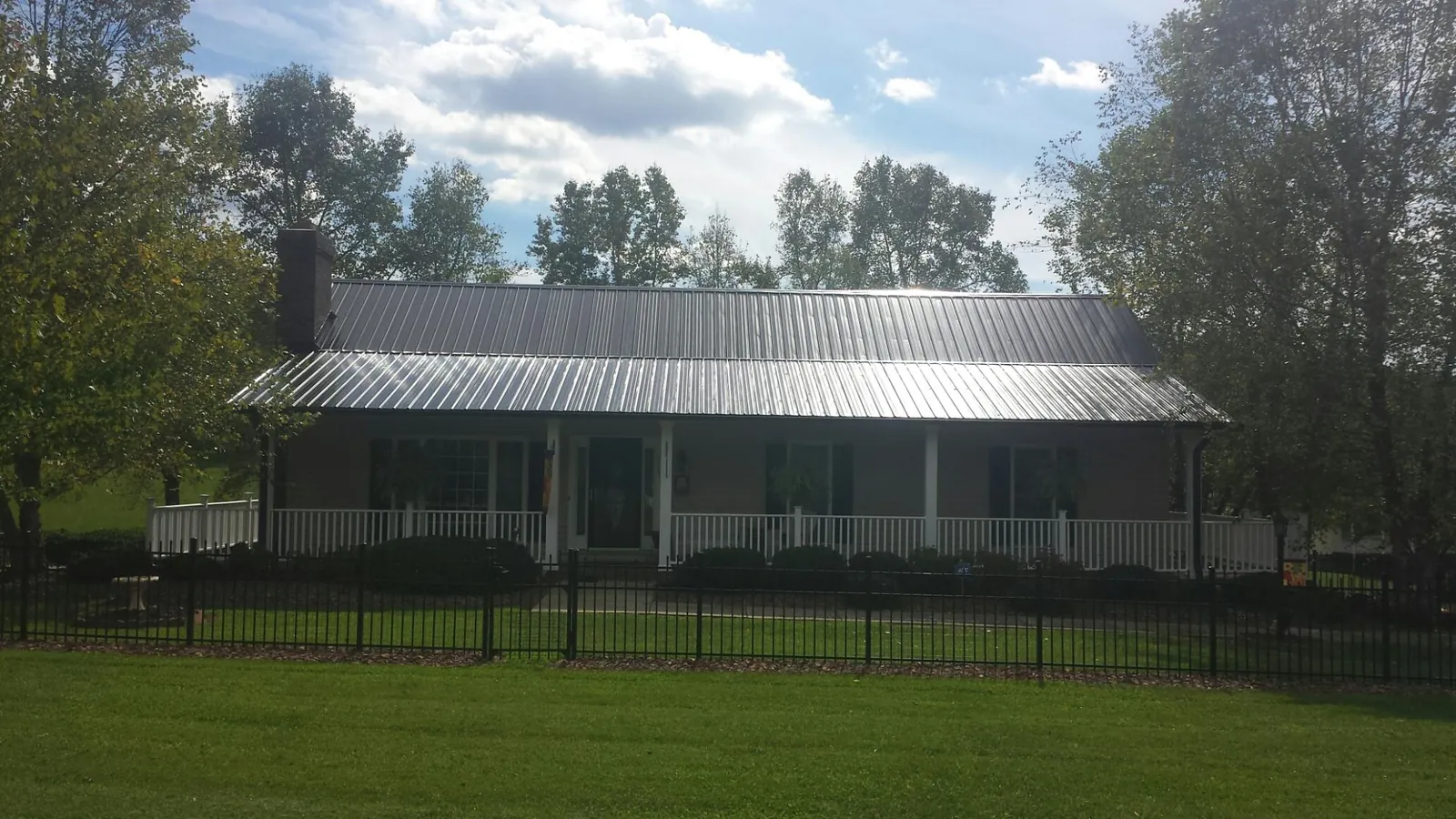 Gray metal roof on a brick ranch with a full width front porch — Gutter Guard Installation work by our crew in Center Conway