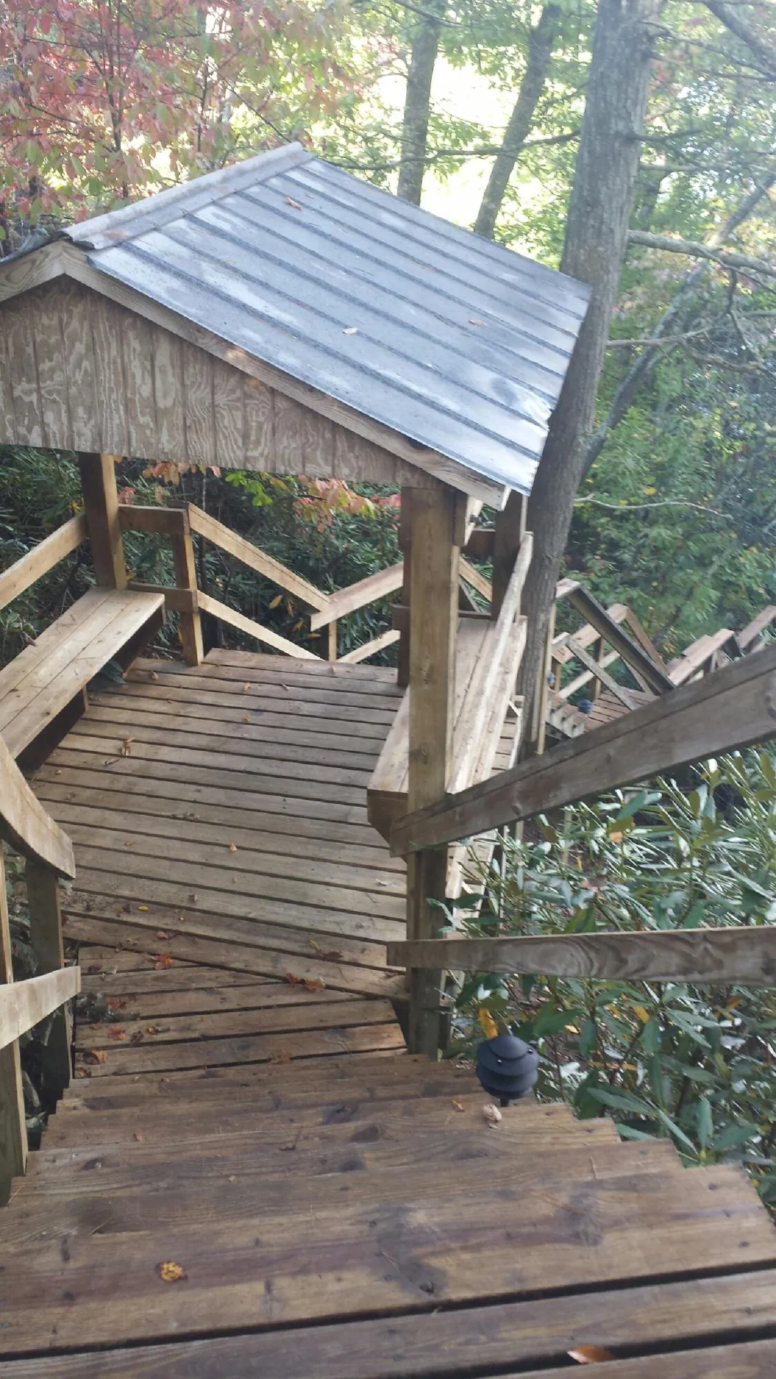 Metal roofed shelter over wooden steps on a wooded walkway — Skylight Repair & Installation work by our crew in Center Conway