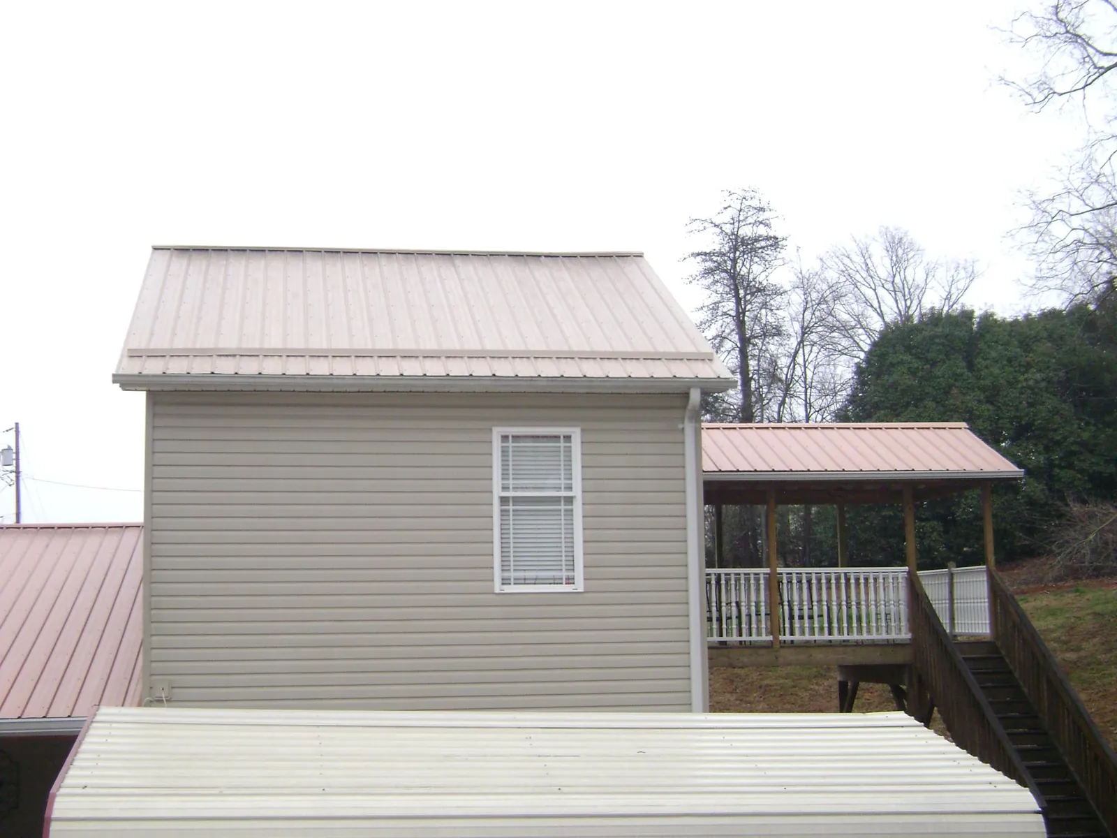 Tan metal roofs on a two story addition and attached porch, from a Roof Replacement job in Center Conway