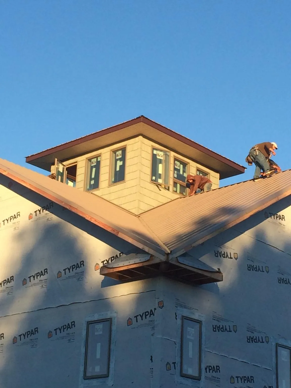 Roofers working around a rooftop cupola on a new metal roof at sunset — Roof Waterproofing in Center Conway by Roofing Brothers